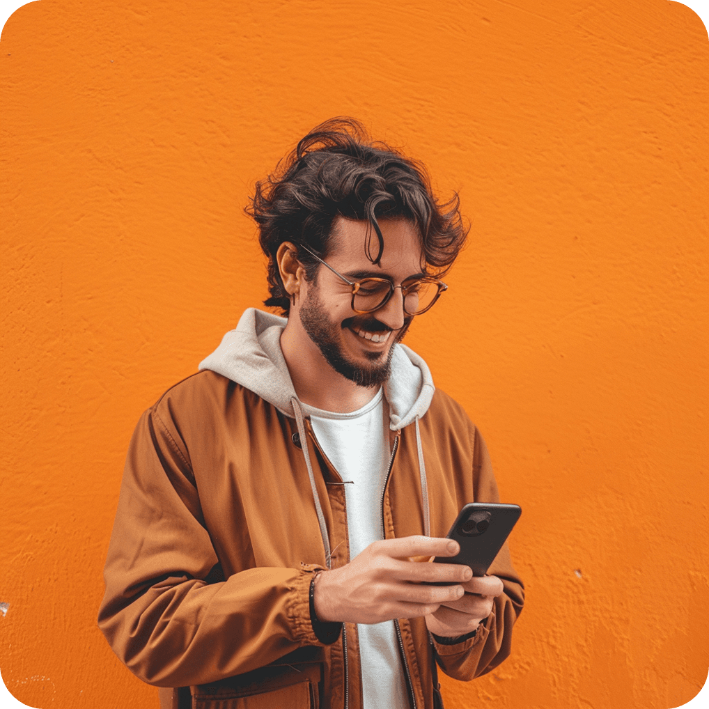 Person in an orange jacket smiling while looking at their phone